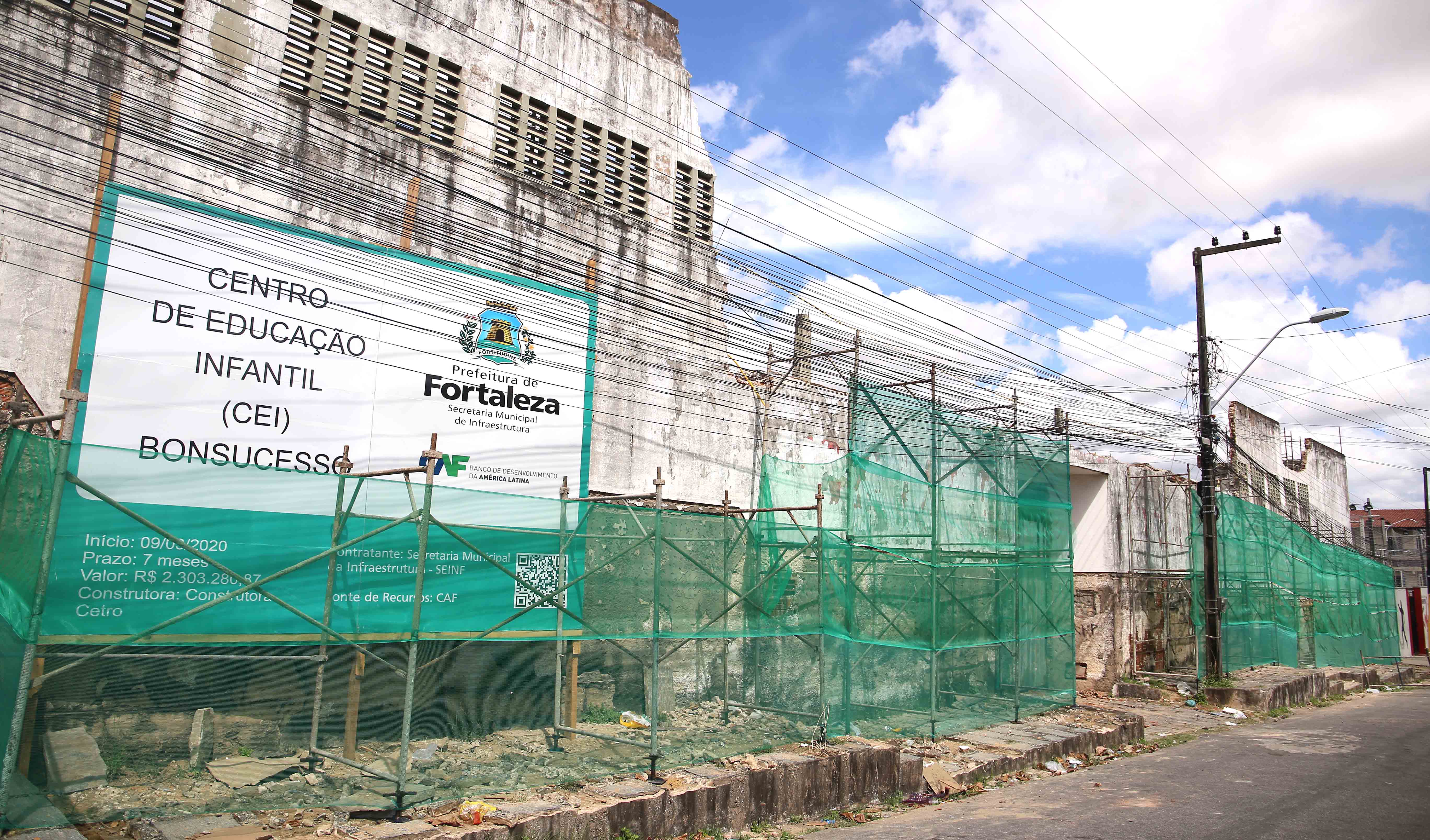 imóvel velho em demolição com placa na calçada com informações da obra